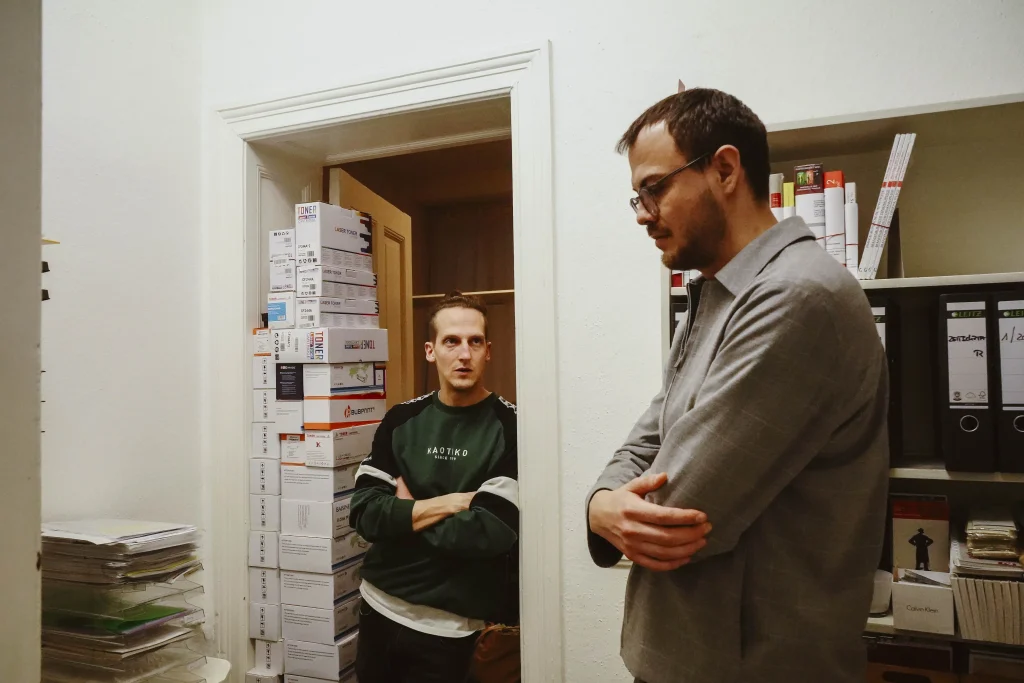 Projektmitarbeiter und Mitarbeiter der Buchhandlung im Gespräch im Kopier- und Aktenraum der Buchhandlung